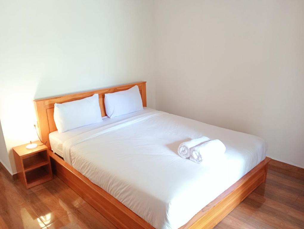 Schlafzimmer mit einem weißen Bett mit einem Kopfteil aus Holz in der Unterkunft Jepun Homestay Lemukih in Singaraja
