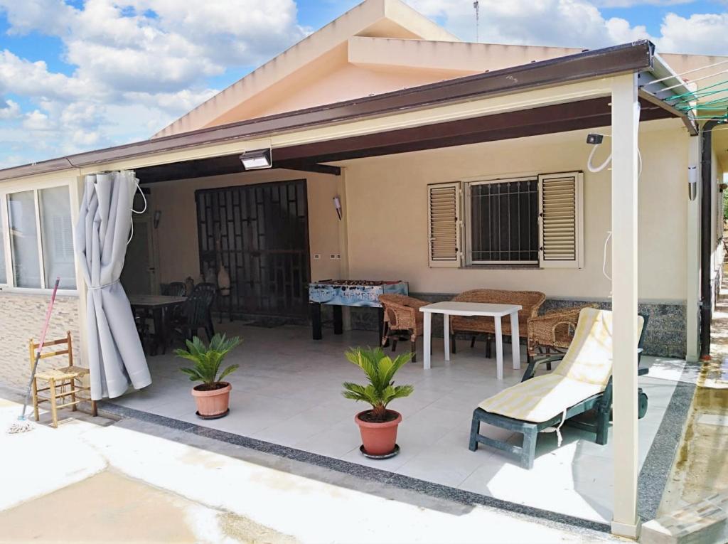 un patio coperto con tavolo e sedie di 3 bedrooms house with sea view and enclosed garden at Menfi 1 km away from the beach a Menfi