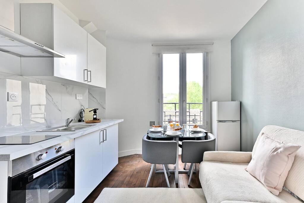 - une cuisine blanche avec une table et un canapé dans l'établissement Peaceful Apartment next to Paris - Gagny, à Gagny