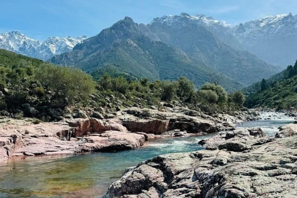 une rivière avec des rochers et des montagnes en arrière-plan dans l'établissement Maison authentique corse, à Manso
