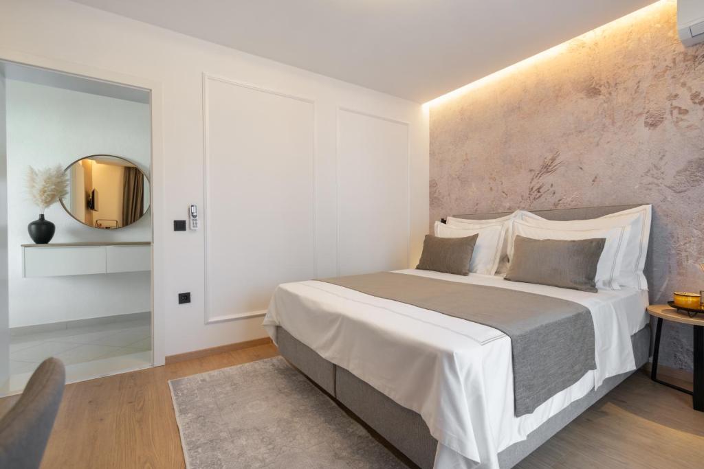 een witte slaapkamer met een groot bed en een spiegel bij Guesthouse Čivljak in Baška Voda