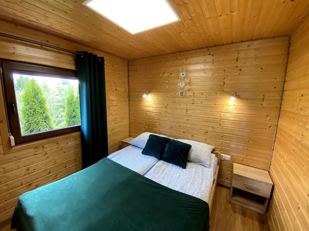 um quarto com uma cama num quarto de madeira em Bieszczadzkie domki z widokiem 793-903-243 em Bukowiec