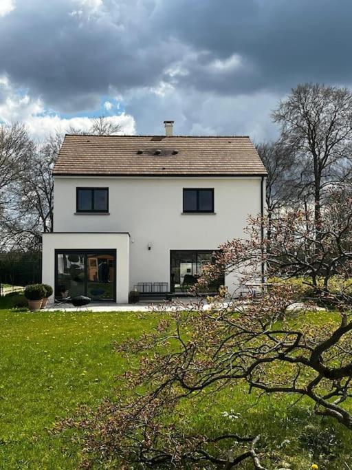 une grande maison blanche avec une cour herbeuse dans l'établissement La Casa Familia à Fontainebleau, à Grez-sur-Loing