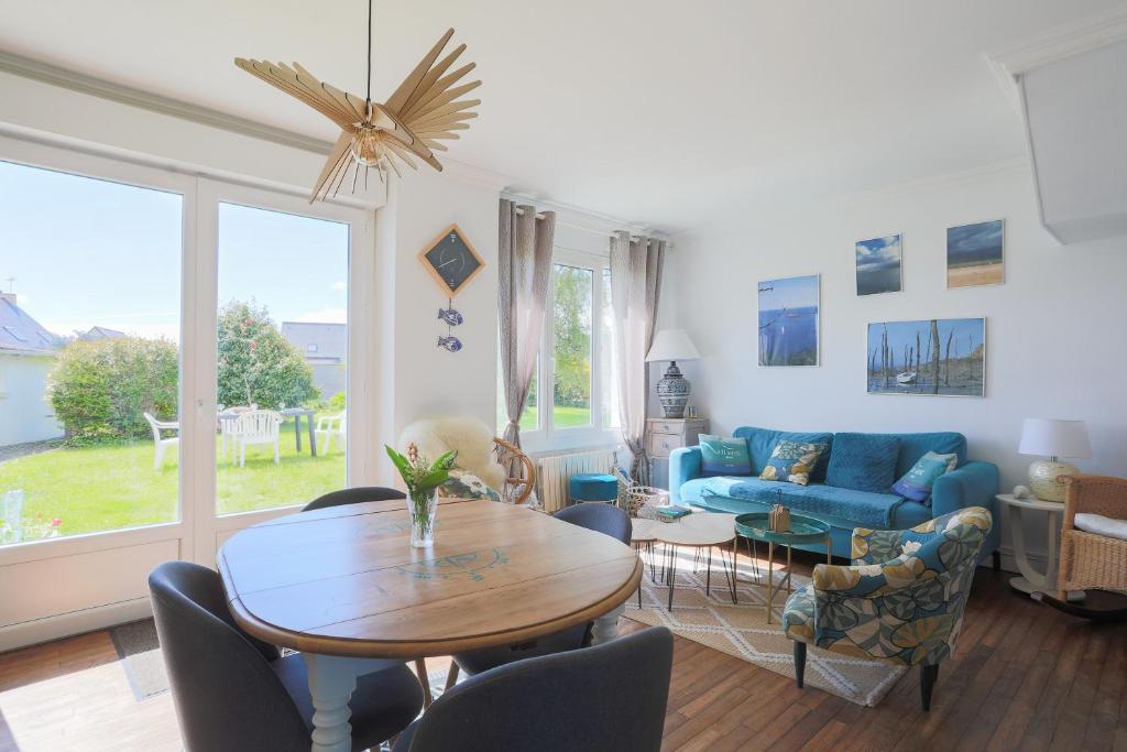 ein Wohnzimmer mit einem Tisch und einem blauen Sofa in der Unterkunft Maison de vacances proche mer in Plouha