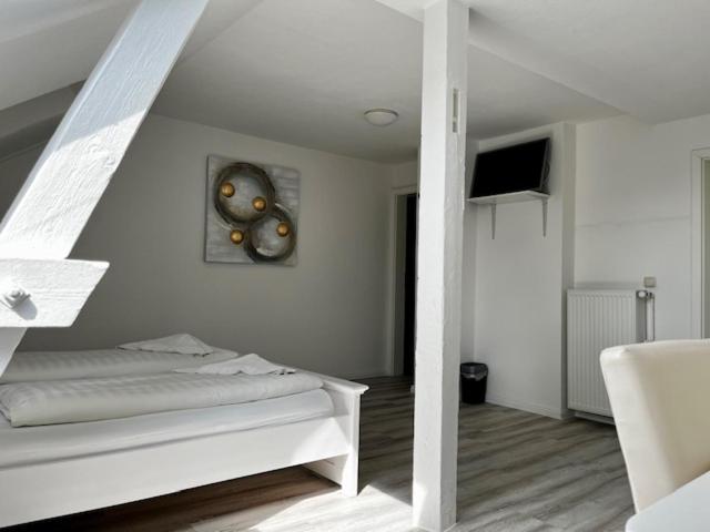Habitación blanca con cama y reloj en la pared en Hotel Lübecker Hof, en Lüneburg