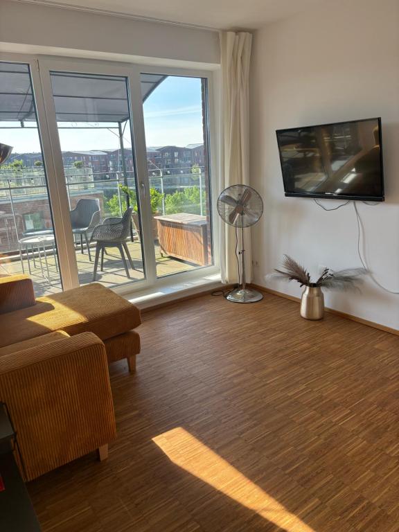 ein Wohnzimmer mit einem großen Fenster und einem TV in der Unterkunft Penthouse-Wohnung mit Flussblick in Oldenburg