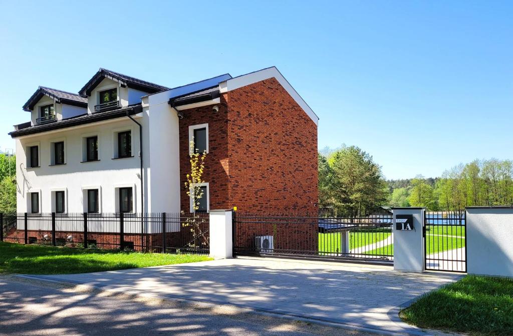 a white house with a red brick building at Trzy Fale in Dąbrówno