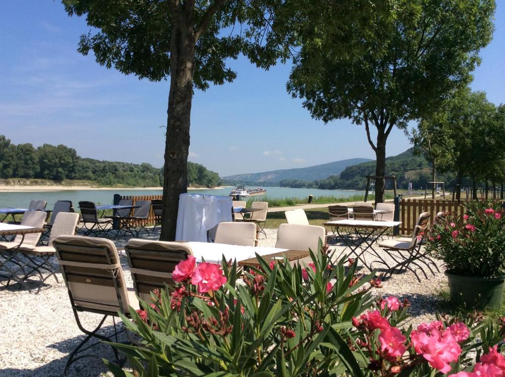 un patio avec des tables et des chaises à côté d'un lac dans l'établissement Gasthof zum Goldenen Anker, à Hainburg an der Donau