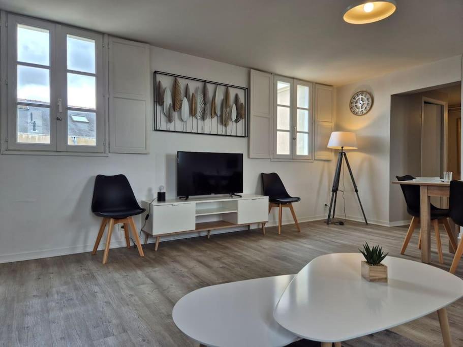 un salon avec une télévision, une table et des chaises dans l'établissement les carmes, à Angers