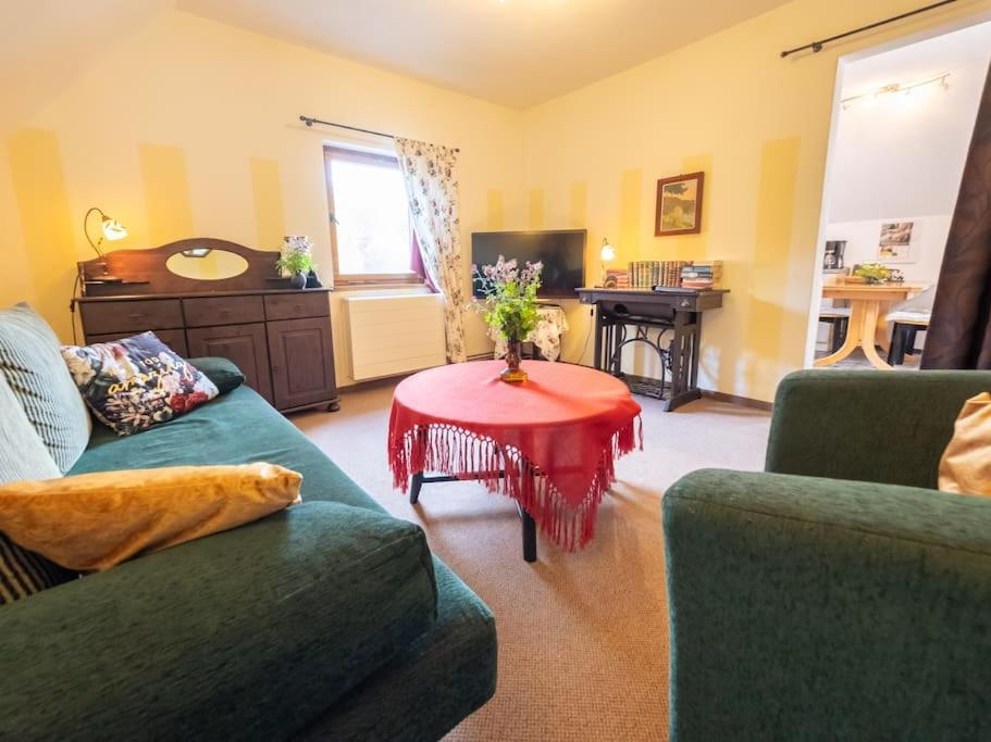 a living room with two green couches and a red table at Gartentraum, Feuergrill, Kids-Spielwelt, 4Räume in Hartenstein