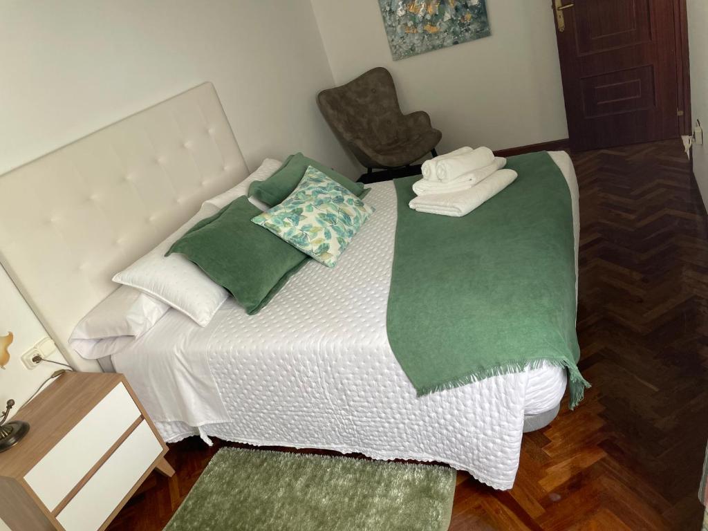 a small bed with green and white sheets and pillows at Piso O Percebe in Muxia