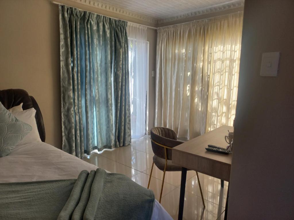 a bedroom with a bed and a desk and a window at Achimer guesthouse in Kroonstad