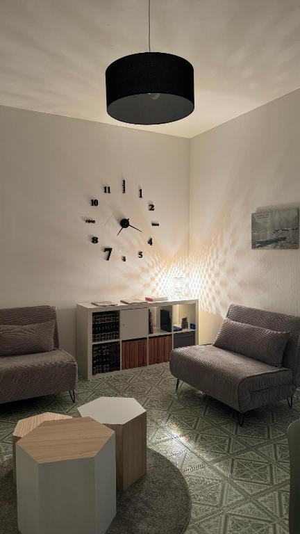 a living room with two couches and a clock on the wall at Green House Calolziocorte in Calolziocorte