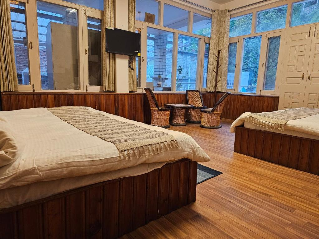 a bedroom with two beds and a flat screen tv at Drifters Inn - The Hidden Tribe in Manāli