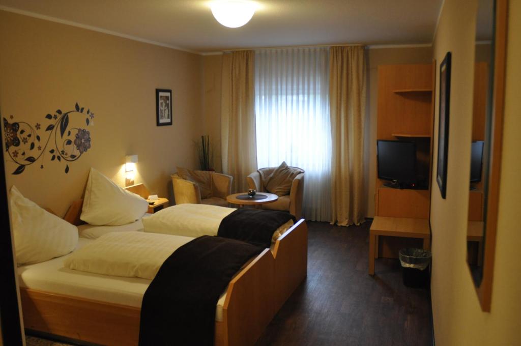 a hotel room with two beds and a television at Hotel Restaurant Byblos in Nordwalde