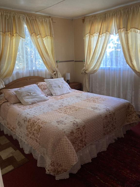 1 dormitorio con 1 cama grande con cortinas y ventana en Cabaña independiente, en Coyhaique
