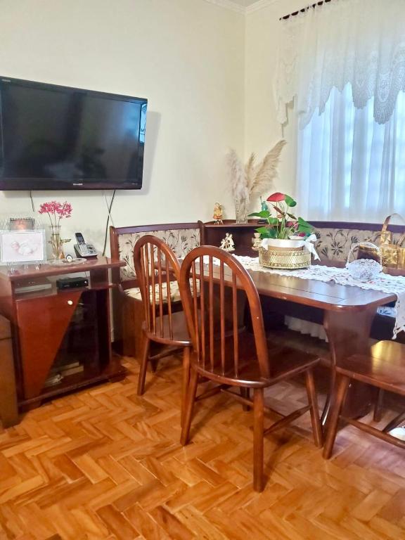 a dining room with a table and chairs and a television at Rios Home in Poços de Caldas