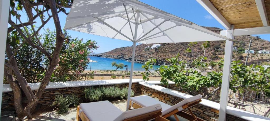 a patio with chairs and an umbrella and the beach at Diana's Luxury Suites in Kithnos