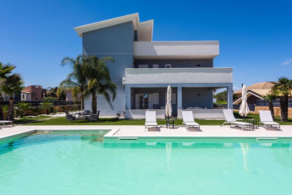 a villa with a swimming pool in front of a house at Etna Mare Apartments by Wonderful Italy in Augusta