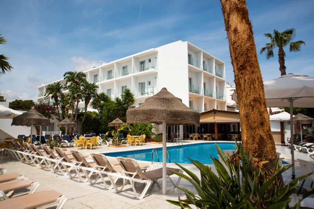 a resort with a pool and chairs and a building at Hostal Mar y Huerta in Es Cana
