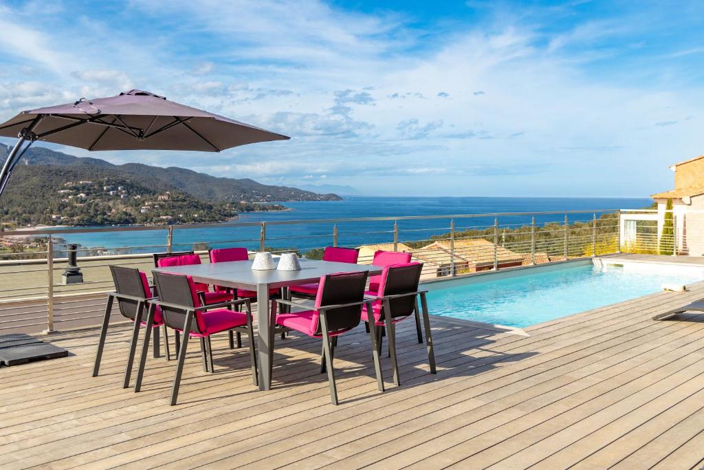 une table avec des chaises roses et un parasol sur une terrasse dans l'établissement Villa Albizia 6P, private heated pool sea view 5 minutes from Favone Beach, à Conca