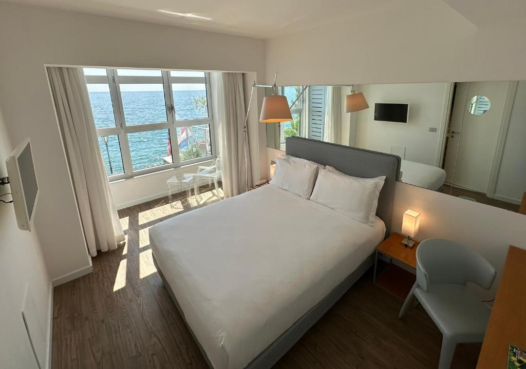 a bedroom with a bed and a desk and a window at Hotel Miramare - Adults Only in Trieste