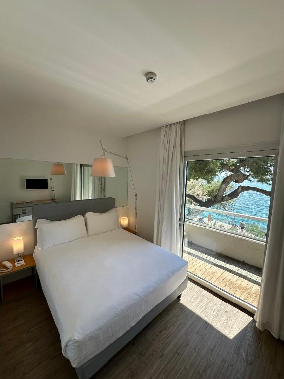 a bedroom with a bed and a view of a beach at Hotel Miramare - Adults Only in Trieste