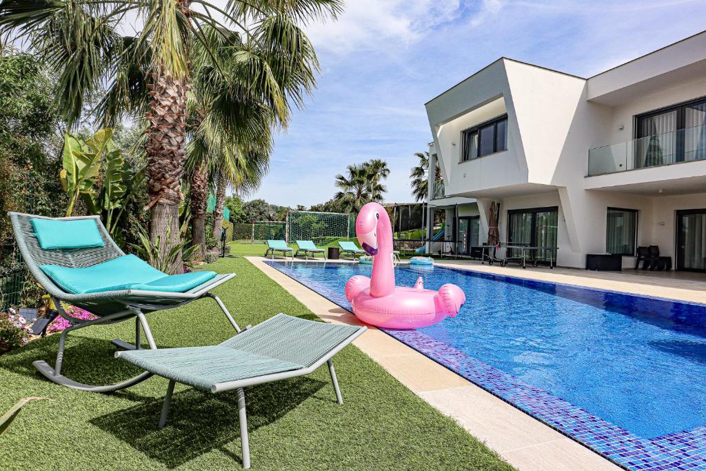 une piscine avec un flamant gonflable rose en face d'une maison dans l'établissement Villa Moroz - BY BEDZY, à Almancil