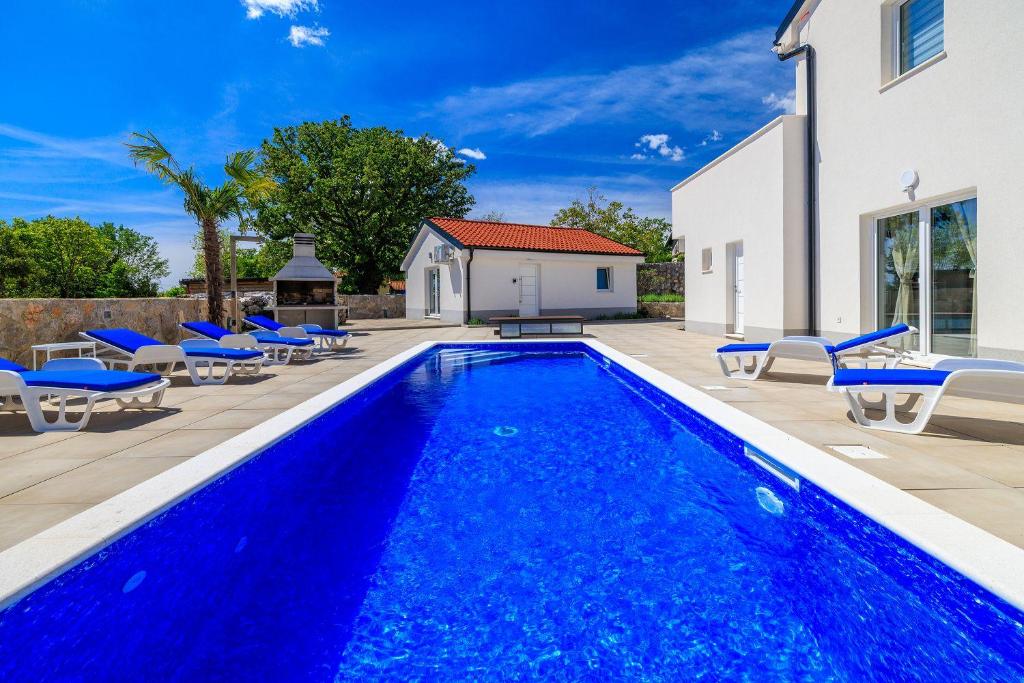 a swimming pool with blue chairs and a house at Pool mit Salzektrolyse unweit der Heilschlamm Bucht in Kras