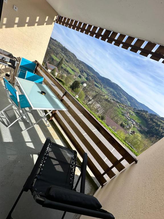 a balcony with a table and chairs and a view at Le Nichoir in Le Tholy