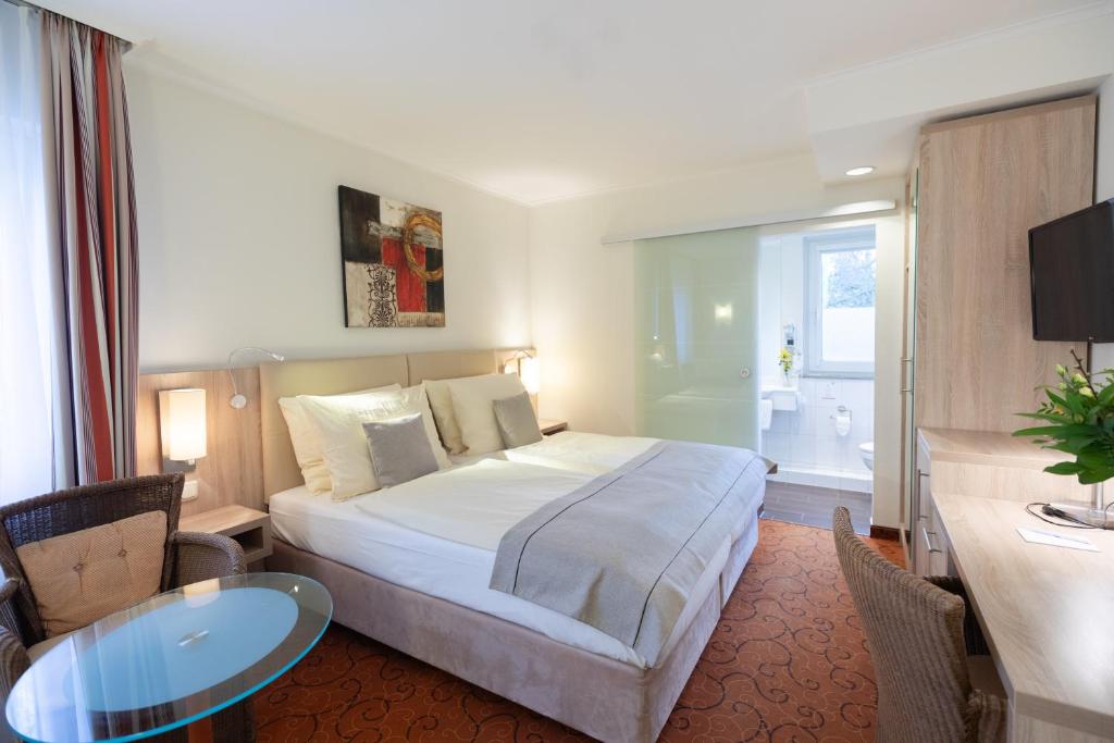ブレーメンにあるNovum Hotel Garden Bremen - Apartmentsのベッド、テーブル、バスルームが備わるホテルルームです。