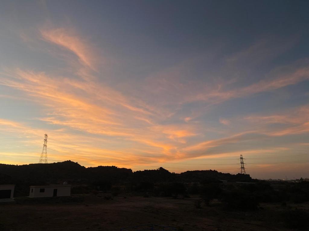 een zonsondergang met twee zendmasten in de lucht bij شقق الزهور in Al Wadeen