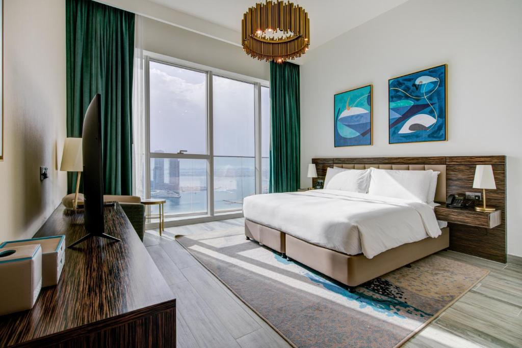 a bedroom with a bed and a large window at Avani Plus Palm View Dubai Suites in Dubai