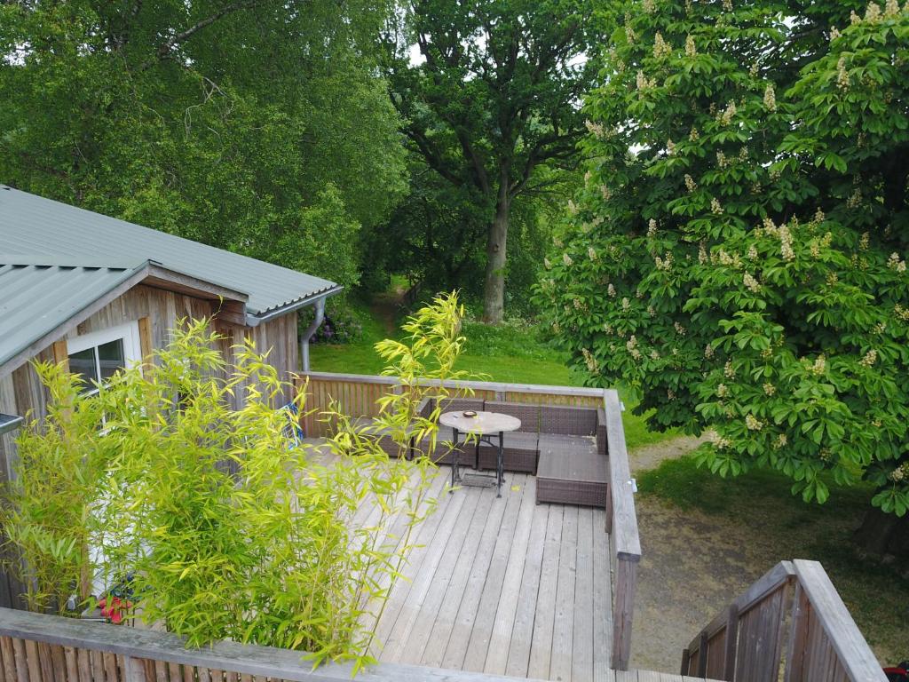 une terrasse en bois avec une table et des chaises. dans l'établissement Urlaub im Alten Apfelgarten - Ferienwohnung Kastanienterrasse, à Sörup