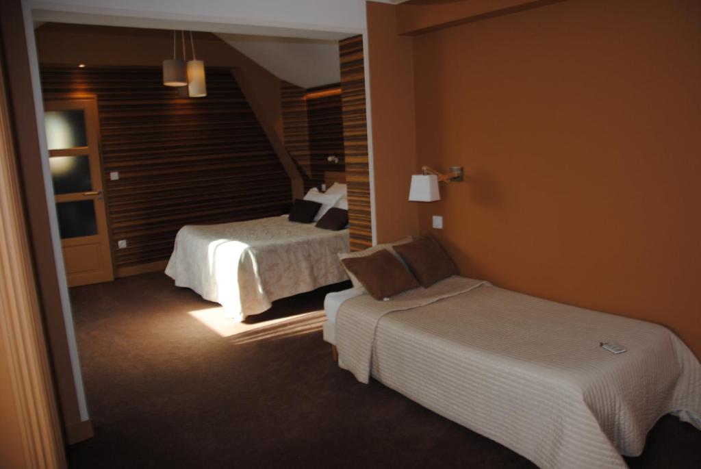 a hotel room with two beds and a window at Logis Hotel Du Casino Restaurant Le Mathelia in Vierville-sur-Mer