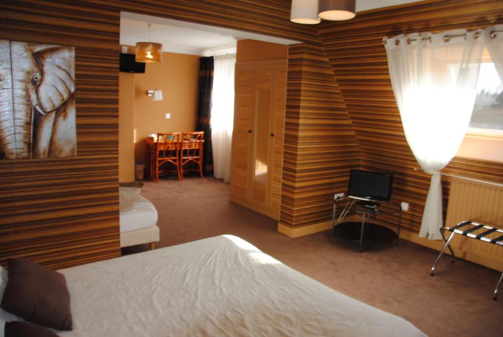 a bedroom with a bed and a television in a room at Logis Hotel Du Casino Restaurant Le Mathelia in Vierville-sur-Mer