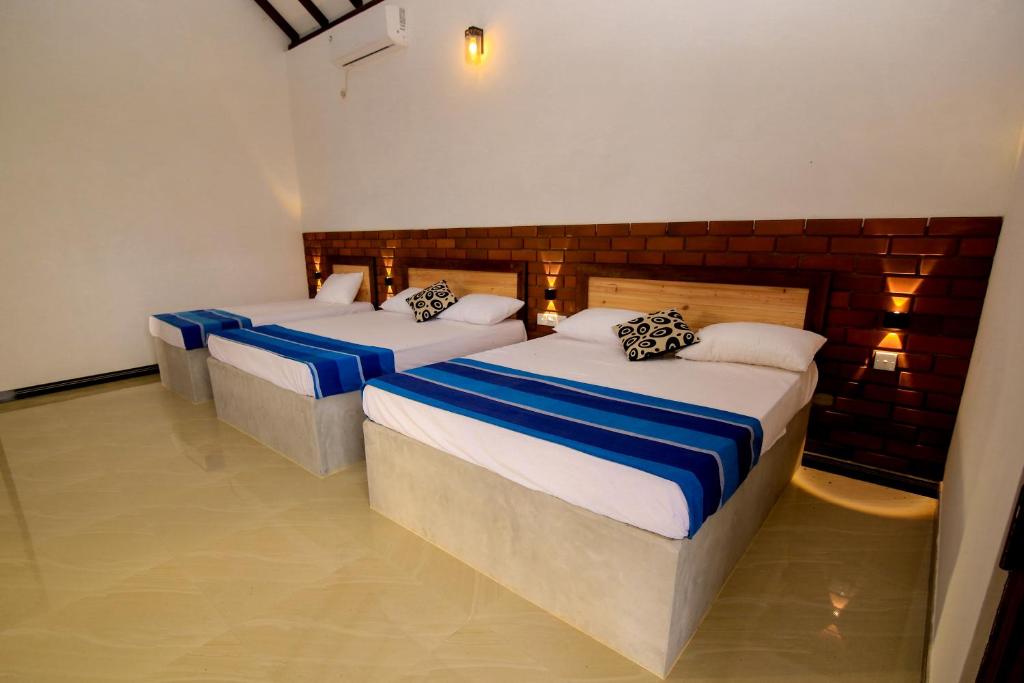Zimmer mit 3 Betten mit blauer und weißer Bettwäsche in der Unterkunft ARI Paradise in Anuradhapura