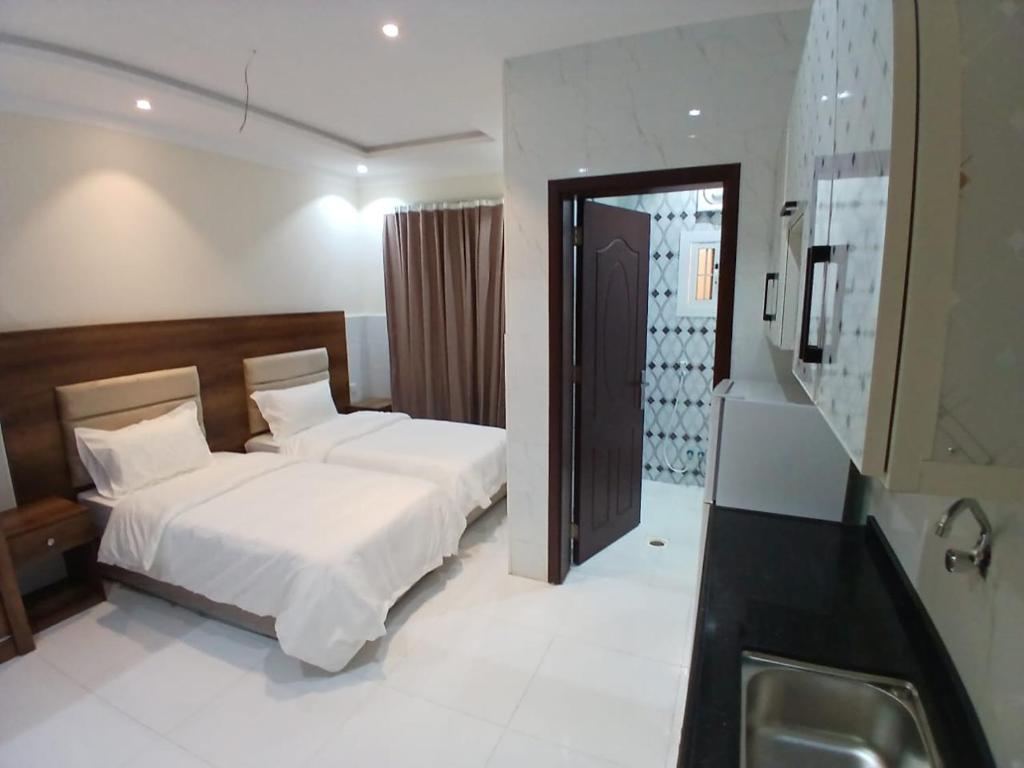 ein Schlafzimmer mit einem Bett und einem Waschbecken darin in der Unterkunft كيان التيسير للشقق المخدومة - Kayan Al Tayseer Serviced Apartments in Quwayzah