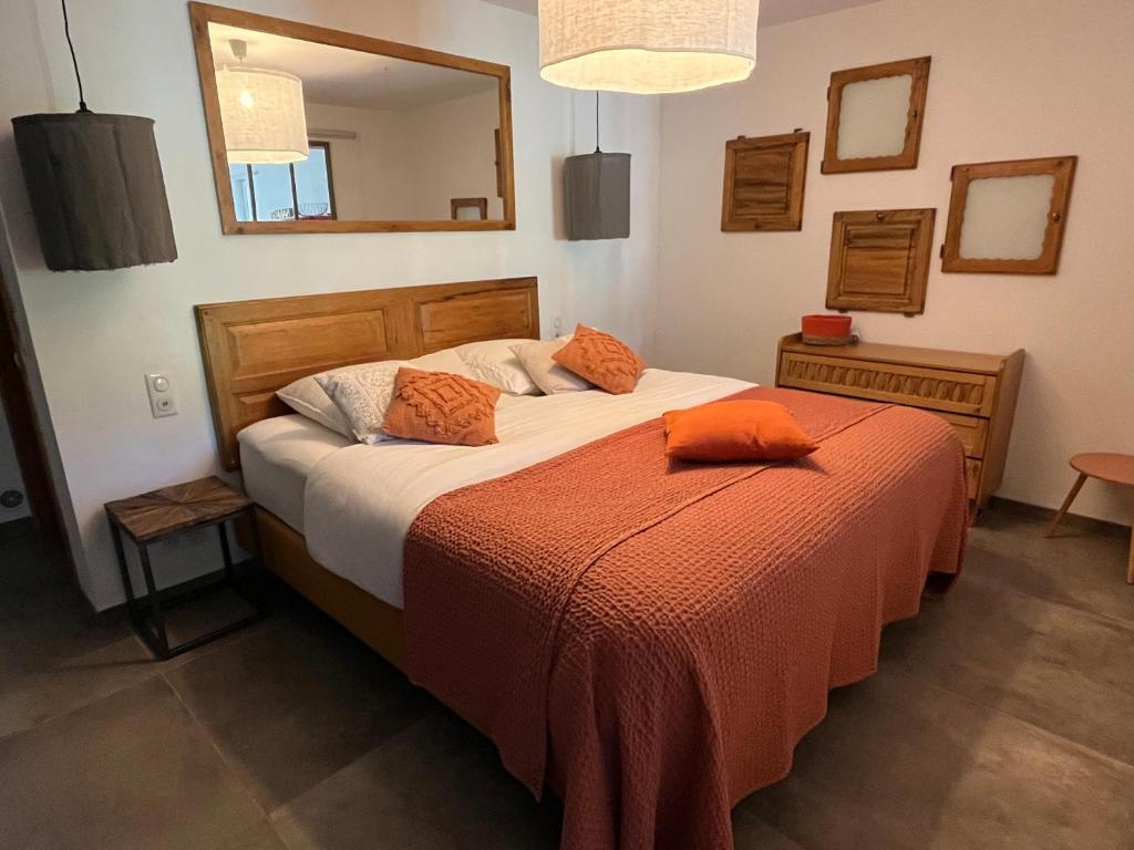 a bedroom with a bed with an orange blanket and a mirror at Hestia in Robion en Luberon