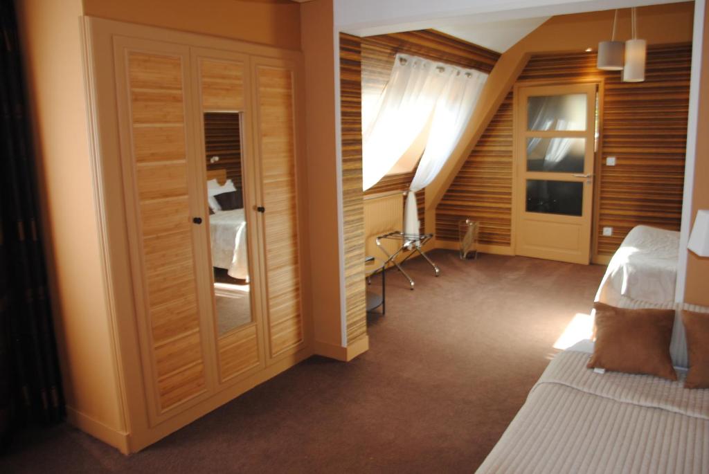 a bedroom with a bed and a staircase with a window at Logis Hotel Du Casino Restaurant Le Mathelia in Vierville-sur-Mer