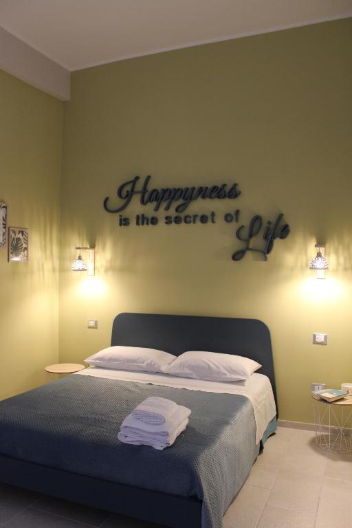 Un letto con un cartello che dice che la felicità è il segreto della vita di HappynessHouse_Locazione turistica a Trani