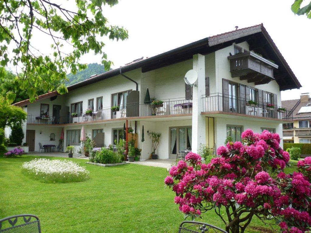 un gran edificio blanco con flores rosas en el patio en Gästehaus Wolfgang, en Ruhpolding