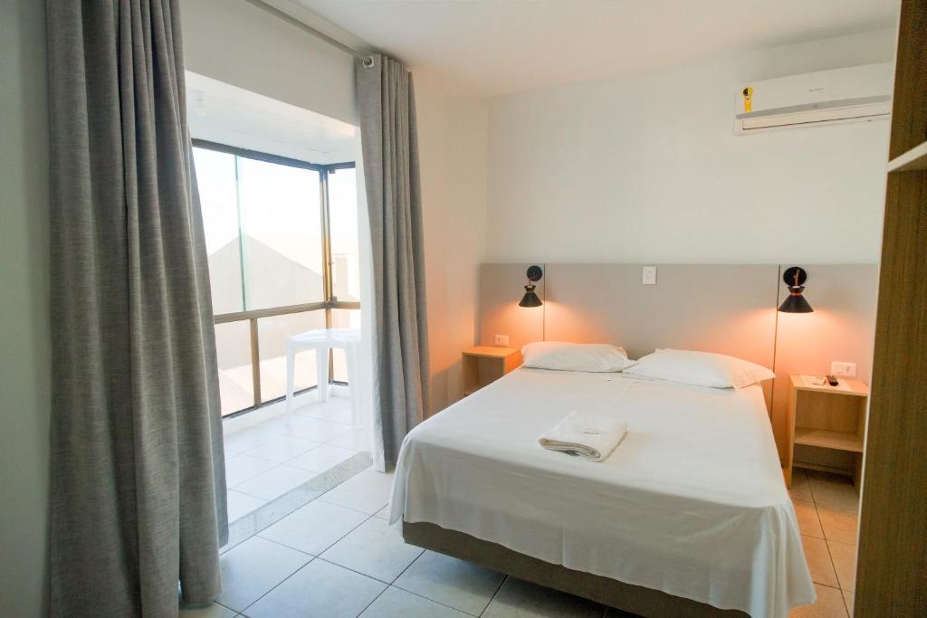 a bedroom with a white bed and a large window at Xangri-La Praia Hotel in Xangri-lá