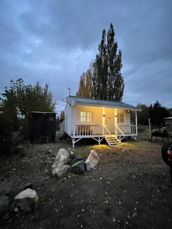 una pequeña casa blanca con porche y algunas rocas en TINY HOUSE Potrerillos en Potrerillos