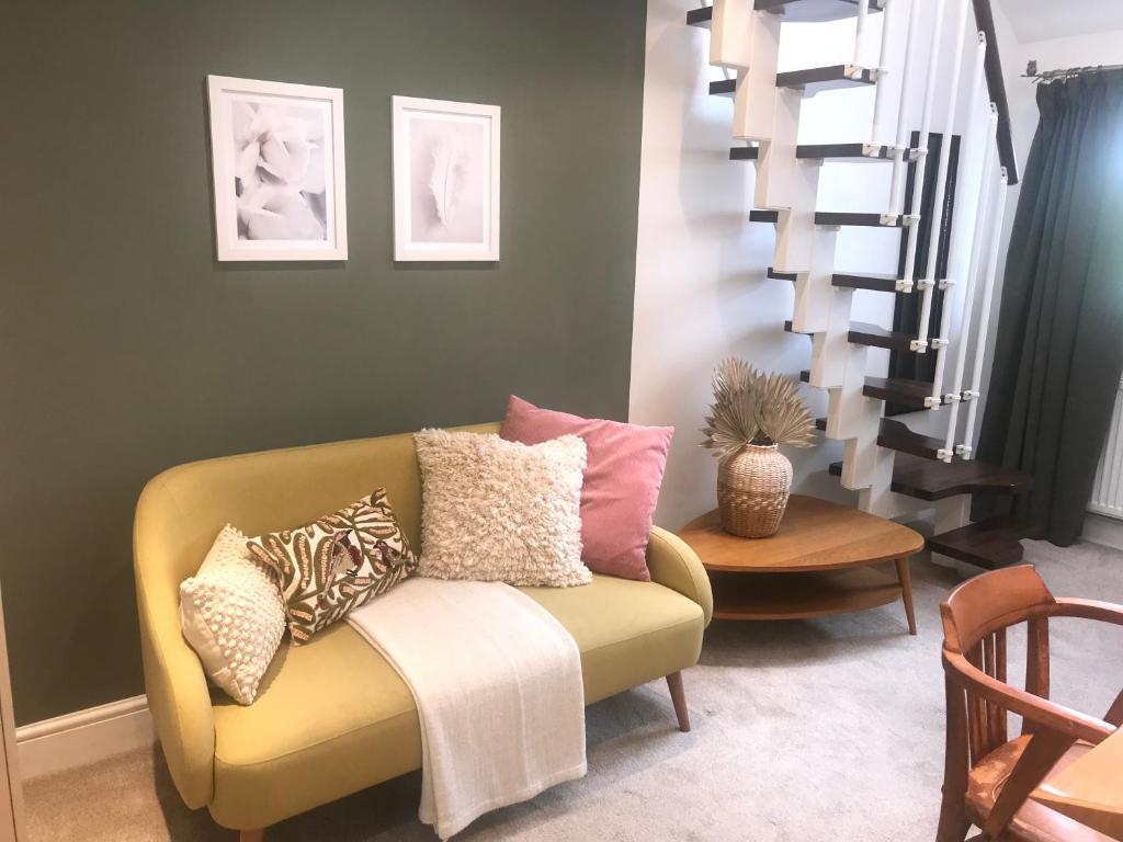 sala de estar con sofá amarillo con almohadas en En-suite with double bed on mezzanine and desk in family home en Hertford