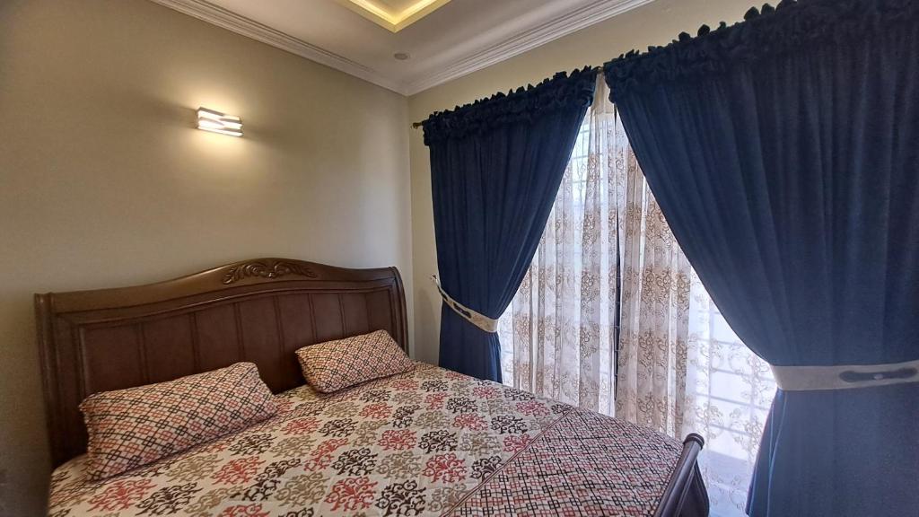 een slaapkamer met een bed en een raam met blauwe gordijnen bij Concept Guest House in Islamabad