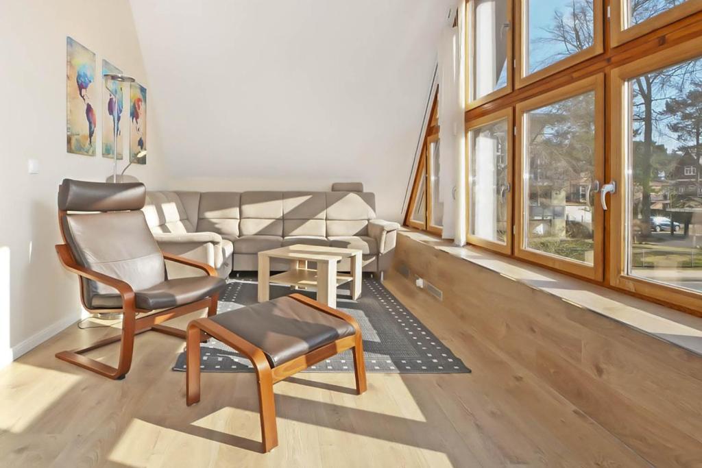 een woonkamer met stoelen en een tafel en ramen bij Apartment Atelier in Bansin