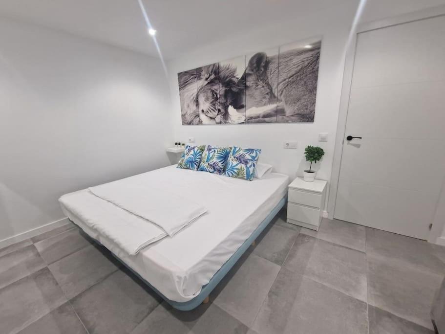 a white bedroom with a bed and a picture on the wall at Casona LOW COST Fan Lujo in Palma de Mallorca