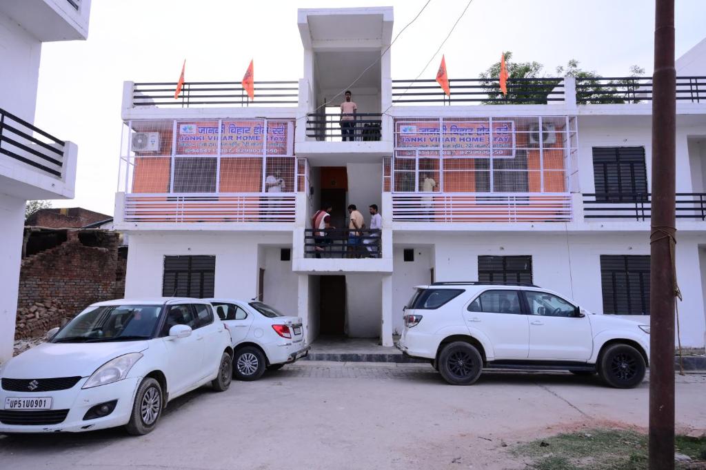Jankivihar Homestay at Prahladghat within 1km from Shri Ram Mandir في Ayodhya: سيارتين بيض متوقفتين امام مبنى