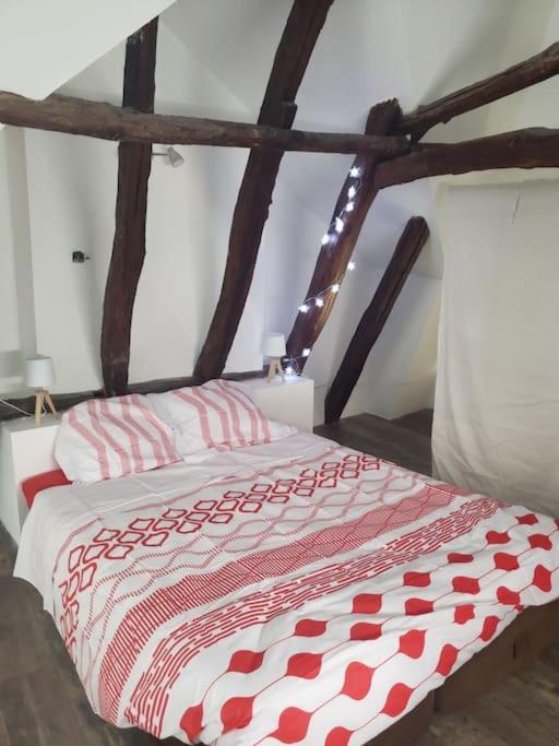 a bed with a red and white quilt on it at Maison du mur jaune in Tourtoirac